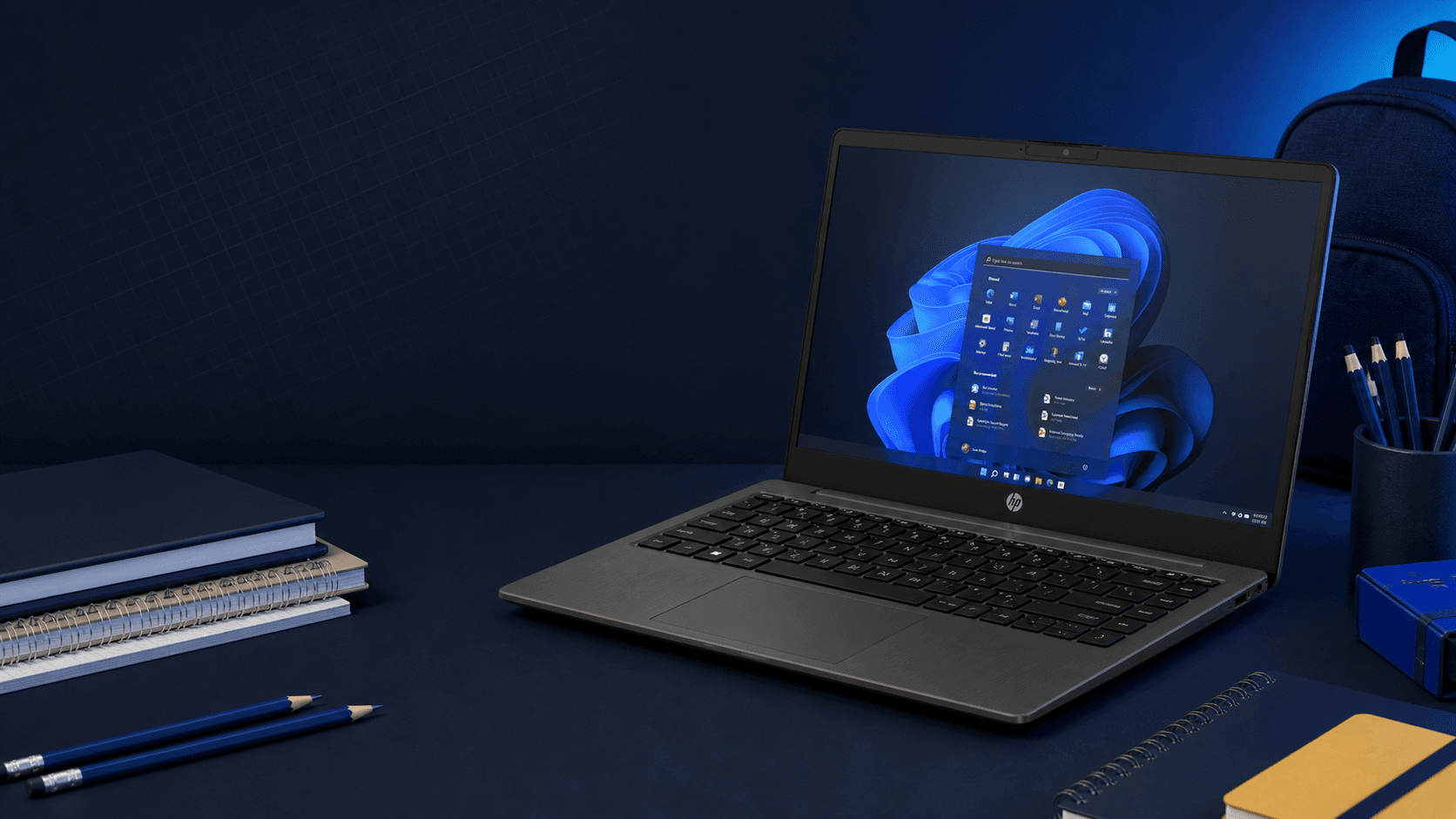 Laptop HP 245 G10 en un escritorio con útiles escolares